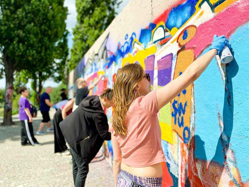 Corporate team building Berlin - employees using gift vouchers for a collaborative graffiti workshop to enhance company culture.